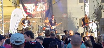 SP25 live - kapela s bannerem